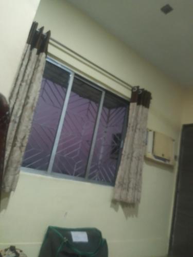 una ventana con cortinas moradas en una habitación en MODI en Calcuta