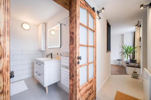 La salle de bains est pourvue d'un lavabo et d'une porte en bois. dans l'établissement L'Éclat de Label Pierre, à Combs-la-Ville