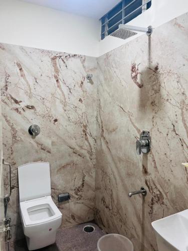 a bathroom with a white toilet and a sink at Hotel Madiwala Grand in Bangalore