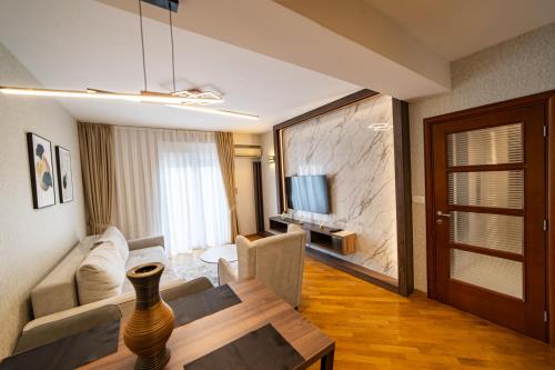 een woonkamer met een bank, een tafel en een televisie bij Apartments 28 in Podgorica