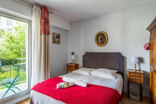 une chambre avec un lit avec une couverture rouge et une fenêtre dans l'établissement Appartement Arazzo - Welkeys, à Versailles
