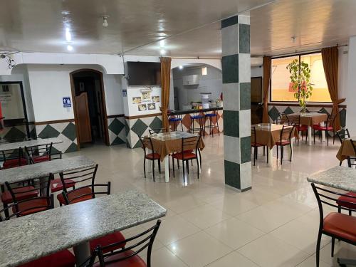 a restaurant with tables and chairs and a kitchen at Hotel Shekinah Internacional in Esmeraldas
