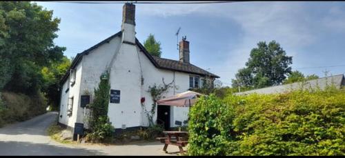a white building with a table and an umbrella at The Northmore Arms in Throwleigh
