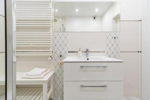a white bathroom with a sink and a shower at Apartament Gąsiorowskich 4 Friendly in Poznań