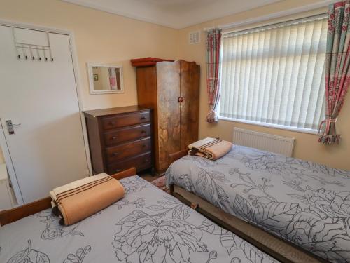 a bedroom with two beds and a dresser and a window at 4 Venables Road in Chester