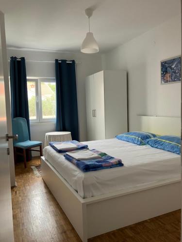 a bedroom with a bed with blue curtains and a chair at Apartment Majda in Rab