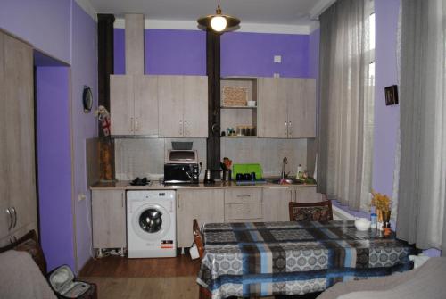 a kitchen with purple walls and a table and a stove at Sweet home in Tbilisi City