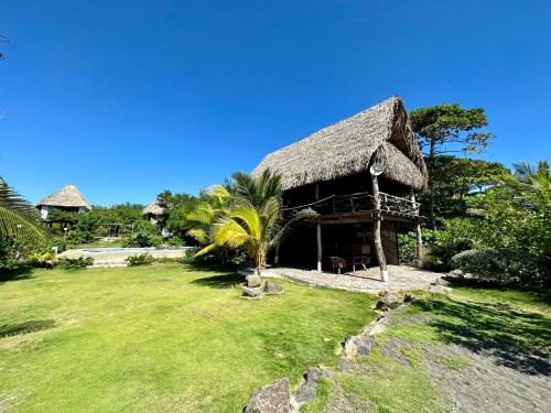 a hut with a grass roof on a lawn at Miravalle Eco Surf in Sonsonate