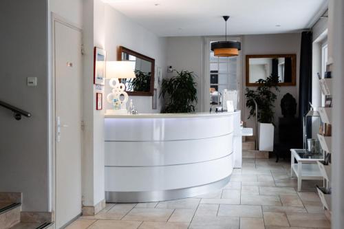 un hall avec un comptoir blanc et quelques plantes dans l'établissement Hôtel Le Tivoli, à Sisteron