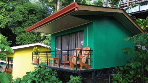 a green and yellow house with chairs on the balcony at Villas In Sueño Private Jungle Hotel in Manuel Antonio