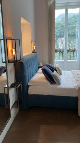a bedroom with a bed with a blue headboard and a window at Calamarina B&B in Vietri sul Mare