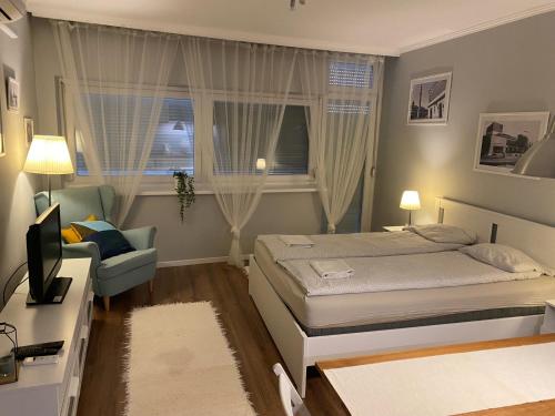 ein Schlafzimmer mit einem Bett, einem Stuhl und einem TV in der Unterkunft B&B Apartman Eger in Eger