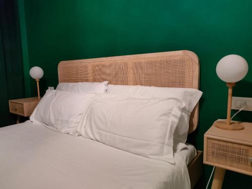 a bed with white pillows and a green wall at Residenza Sant'Andrea Smeraldo in Chioggia