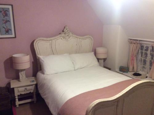 a bedroom with a large white bed with two lamps at Mermaid Cottage in West Lulworth