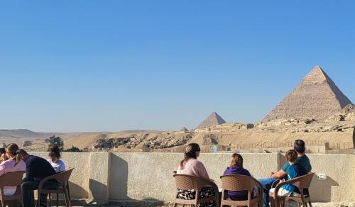 a group of people sitting in chairs looking at the pyramids at AliBaba Pyramids View Inn in Cairo