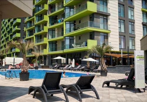 un hôtel avec une piscine, des chaises et un bâtiment dans l'établissement Summerland apartments and Alezzi apartments, à Mamaia