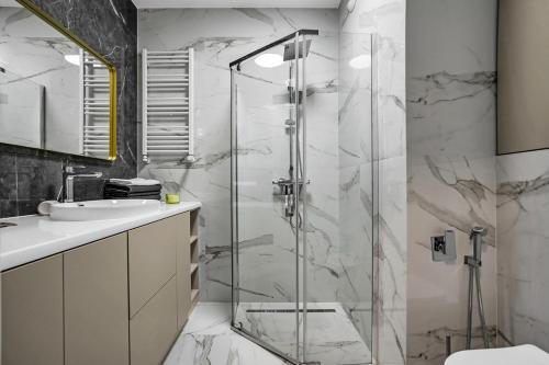 La salle de bains est pourvue d'une douche en verre et d'un lavabo. dans l'établissement Airport Apartment - Private Terrace & Parking - by Rentujemy, à Varsovie