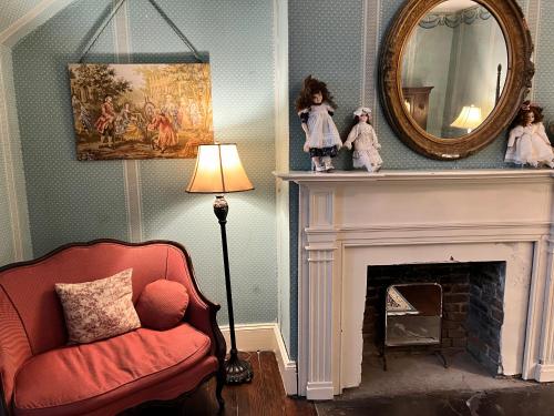 a living room with a red chair and a mirror at The Myrtles in Saint Francisville