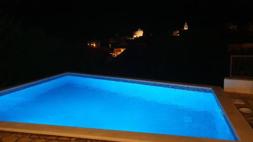 a blue swimming pool at night at Villa Neptune Apartments in Vrboska