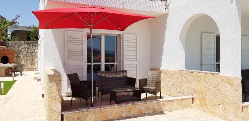 a group of chairs and a red umbrella on a patio at Villa Neptune Apartments in Vrboska