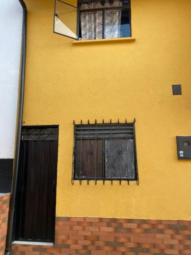 a yellow building with a gate and a window at Apartaestudio Bellapalma Socorro Calle 16a # 7-37 in Socorro