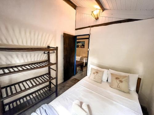 um quarto com uma cama com lençóis brancos e almofadas em Pousada Zen Caraiva em Caraíva