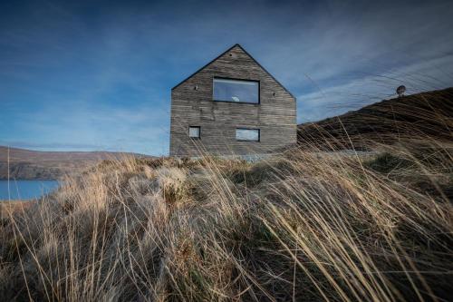 a house on top of a hill with grass at Dark Skye Cottage in Milovaig