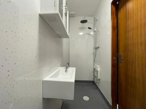 a white bathroom with a sink and a shower at Hidden House Hebrides in Garrabost