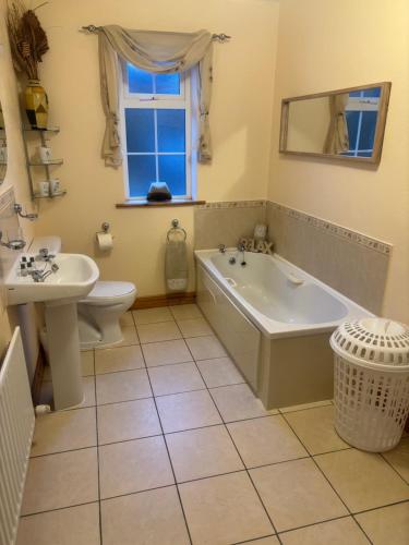 a bathroom with a tub and a toilet and a sink at Tilly's Cottage in Durrus