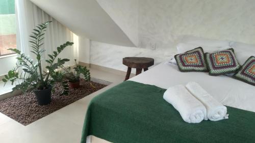 a bedroom with a bed with towels and plants at Chalé Macaúba in Santana do Riacho