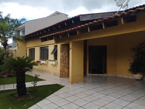 a yellow house with a porch and a courtyard at Aero Hostel in Londrina