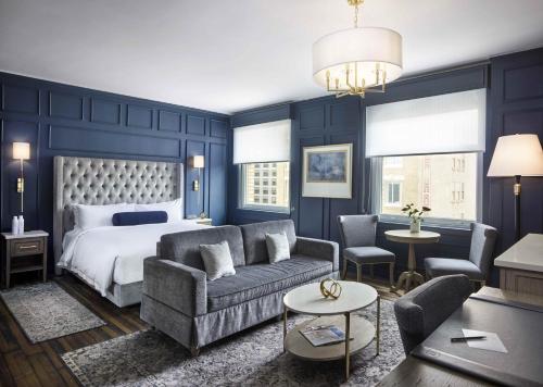 a bedroom with blue walls and a bed and a couch at Beacon Grand, A Union Square Hotel in San Francisco