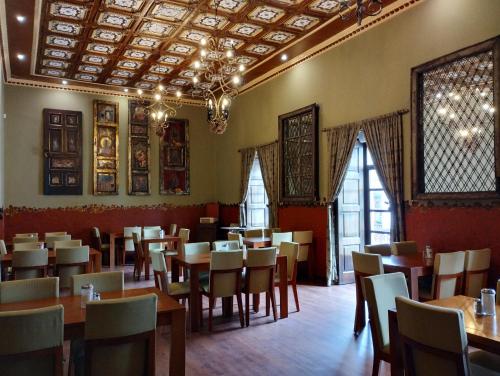 una sala da pranzo con tavoli, sedie e finestre di Hotel Raymipampa a Cuenca