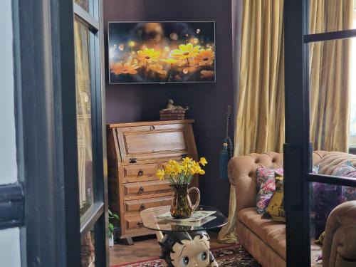 a living room with a dresser and a table with a vase of flowers at Flawsome stays Unique Edwardian Home near the Harbour and town perfect for Families up to 8 guests in Ramsgate