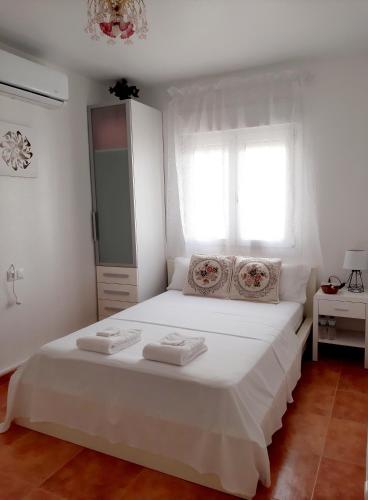 Un dormitorio con una cama blanca con toallas. en Habitación Avileña Tropical en Aguadulce en Almería