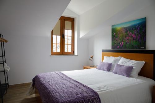 1 dormitorio con 1 cama y una pintura en la pared en Casas do Oiteirinho en Arganil