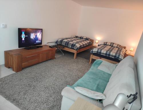 a living room with a couch and a tv and a bed at Gästezimmer La Siesta in Ötisheim