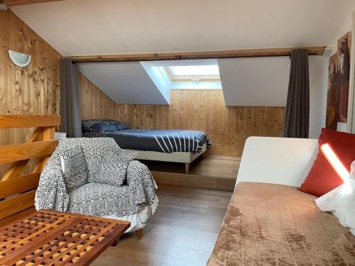 une chambre avec un lit, un canapé et une chaise dans l'établissement Beau Duplex, au bord du lac Saint-Point, à Malbuisson