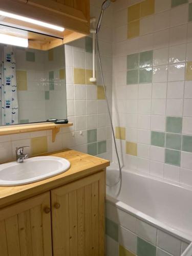 une salle de bain avec un lavabo, une baignoire et un miroir dans l'établissement Beau Duplex, au bord du lac Saint-Point, à Malbuisson