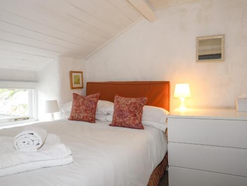 a bedroom with a bed with white sheets and red pillows at Blue Cottage in Beaumaris