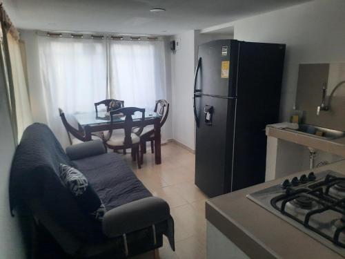 a kitchen with a couch and a refrigerator and a table at El Encanto ApartaSuite in Barranquilla