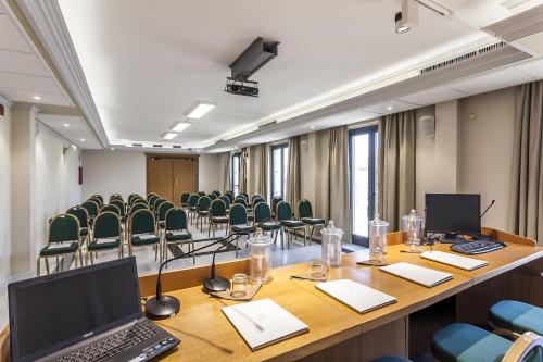 a conference room with a long table with chairs and a laptop at Grand Hotel Bonanno in Pisa