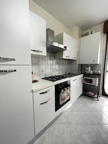 La cuisine est équipée de placards blancs et d'un four avec plaques de cuisson. dans l'établissement Airbnb da Concy, à Zelo Buon Persico