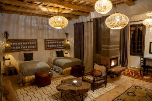 a bedroom with two beds and a table and chandeliers at Eden Boutique Hotel in Tamellalt