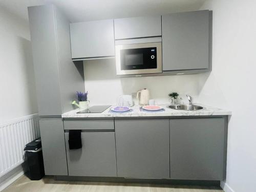 a small kitchen with a sink and a microwave at Sleek & Stylish Stretford Studio for Two in Manchester