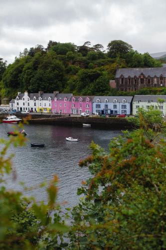 a town with pink houses and boats in the water at Dark Skye Cottage in Milovaig