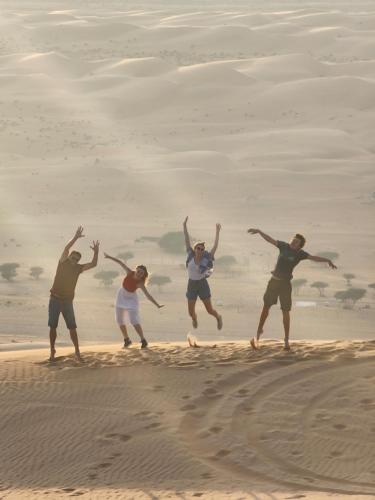 a group of people jumping in the sand at Bubbles Domes Private Cmp in Al Wāşil