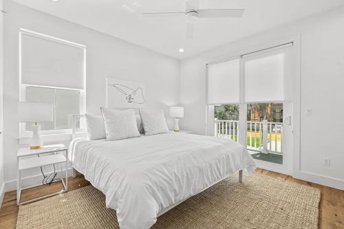 a white bedroom with a large bed and a window at Endless Summer Oasis Heated Pool And Putting Green in Saint Augustine Beach
