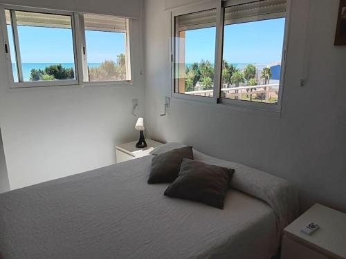 a bedroom with a bed with two pillows and two windows at Apartamento en Xilxes con preciosas vistas al mar in Chilches