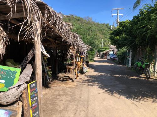 a village street with a thatch roofed building at Hab #5 La Casa Del Profe Salo in Santa María Tonameca